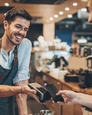 Mann bezahlt mit seinem Smartphone und via Apple Pay seinen Kaffee beim Barrista